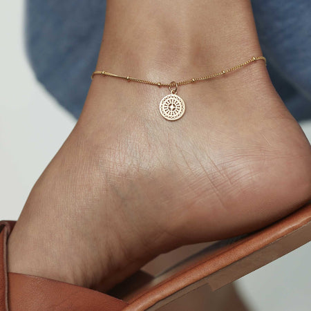 a gold ancient coin anklet sitting on an model's ankle